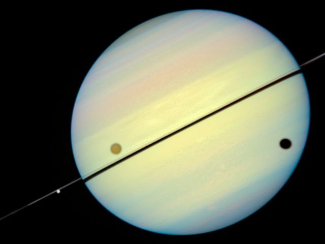Space - Saturn's rings tilt edge-on as Titan casts its shadow